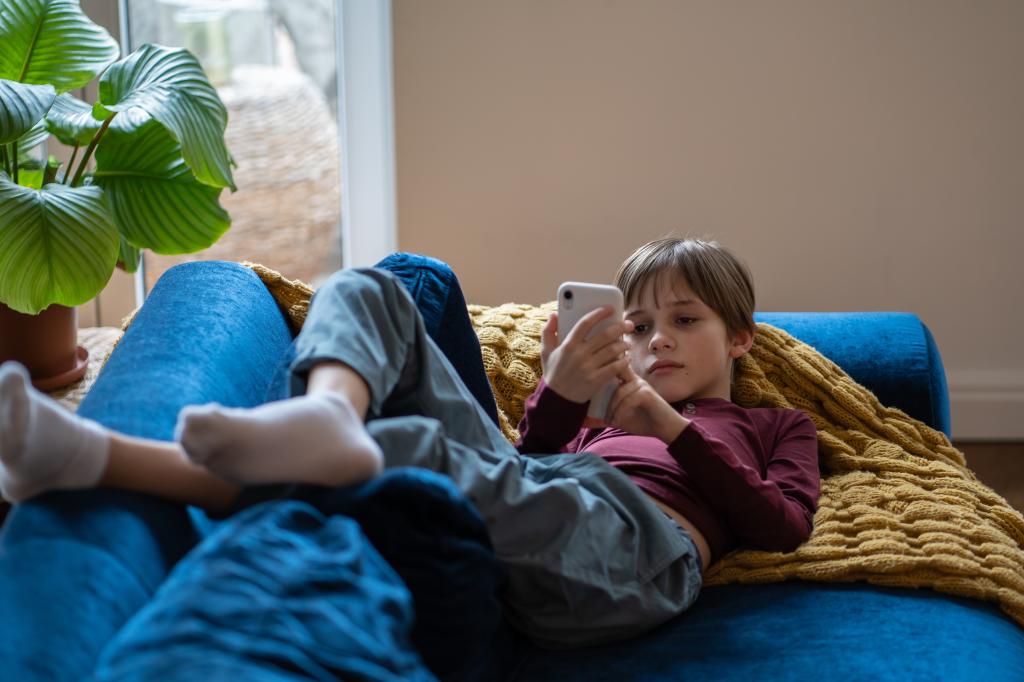 Child laying on couch on phone