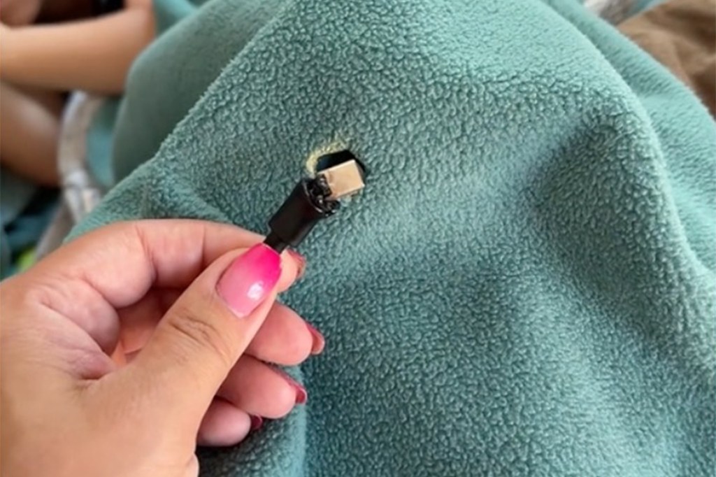 A woman holding a burnt USB-C charging cable that had been lying on a blanket in her home