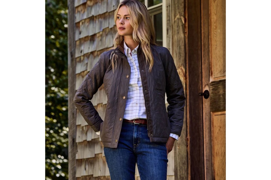 A woman standing outside a house wearing a jacket