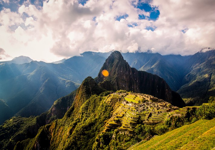 Machu Picchu - tall mountain with bright blue sky and rolling greens