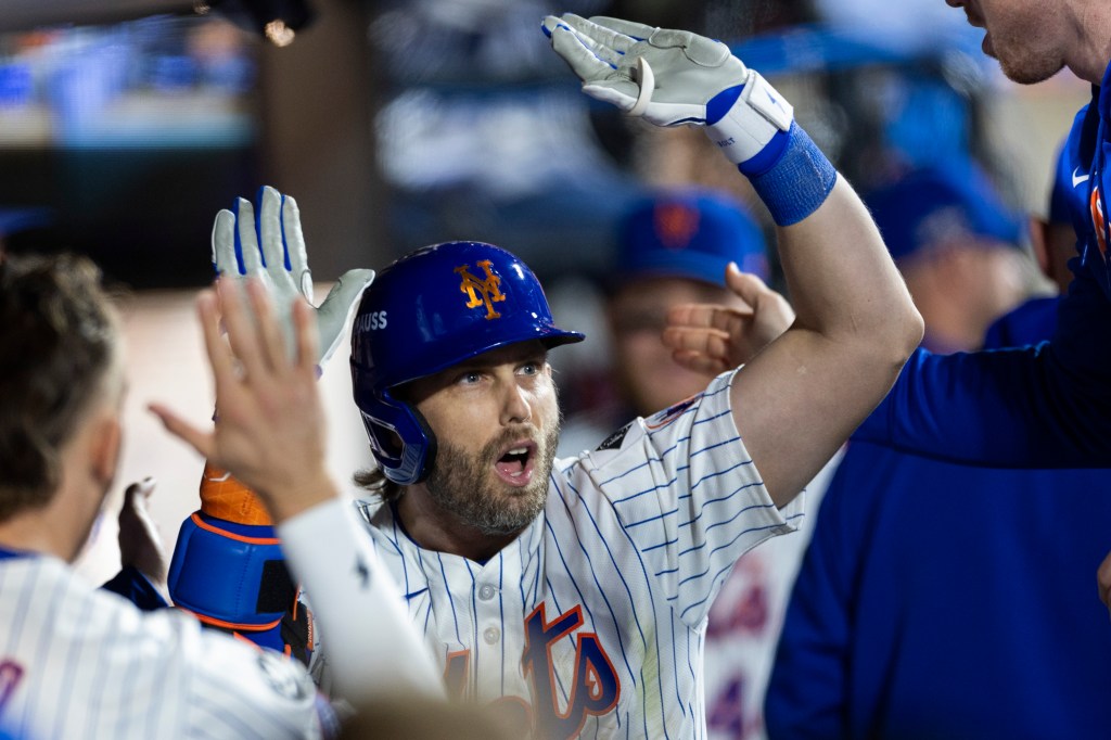 Jeff McNeil of the New York Mets being congratulated in the dugout by teammates after hitting a sacrificial fly leading to a score during a game against the Los Angeles Dodgers