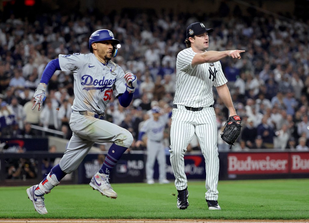 New York Yankees starting pitcher Gerrit Cole #45 points to first as Los Angeles Dodgers shortstop Mookie Betts #50 reacts on an infield single allowing a run to score during the fifth inning.