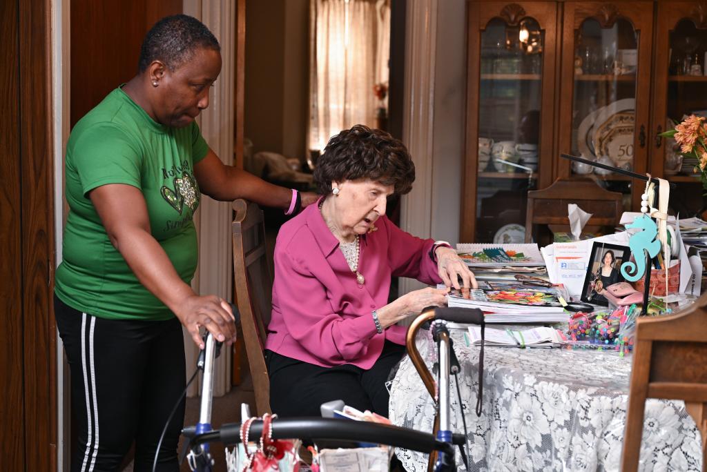 Nigro working on a coloring book as her home aide Karen Lewis looks on.