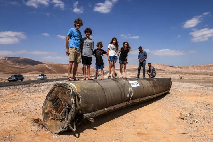 People stand on top of the remains of an Iranian missile in the Negev desert near Arad, on October 2, 2024, in the aftermath of an Iranian missile attack on Israel.