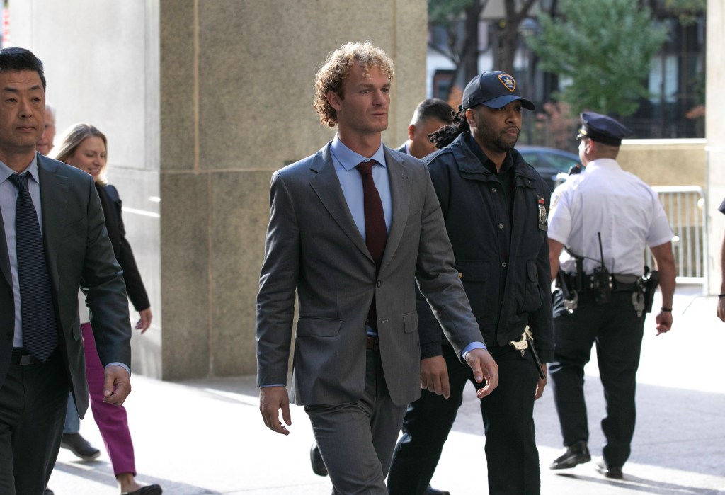 Daniel Penny in a suit arriving at Manhattan Criminal Court, accompanied by police officers, for jury selection in his defense case on October 25, 2024.