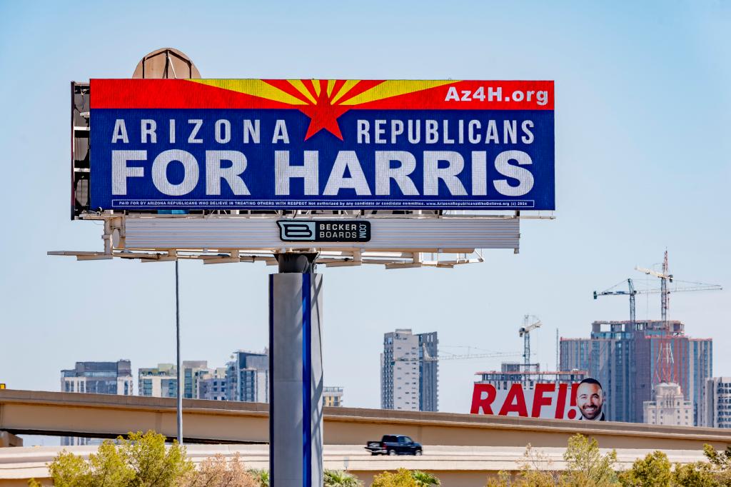 A large billboard reading 'Arizona Republicans for Harris' at a busy intersection of Interstate 17 and Interstate 10 in Phoenix, Arizona, 2024.