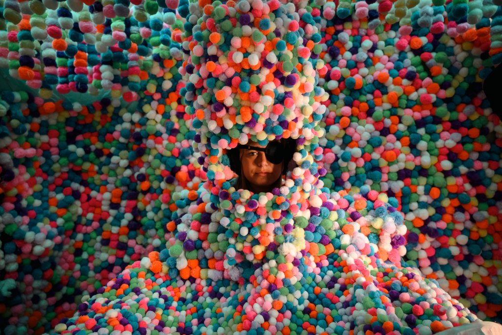 A visitor stares out from the mass of pom-poms at the installation "Bobby Anspach: The Beautiful Nothing ."