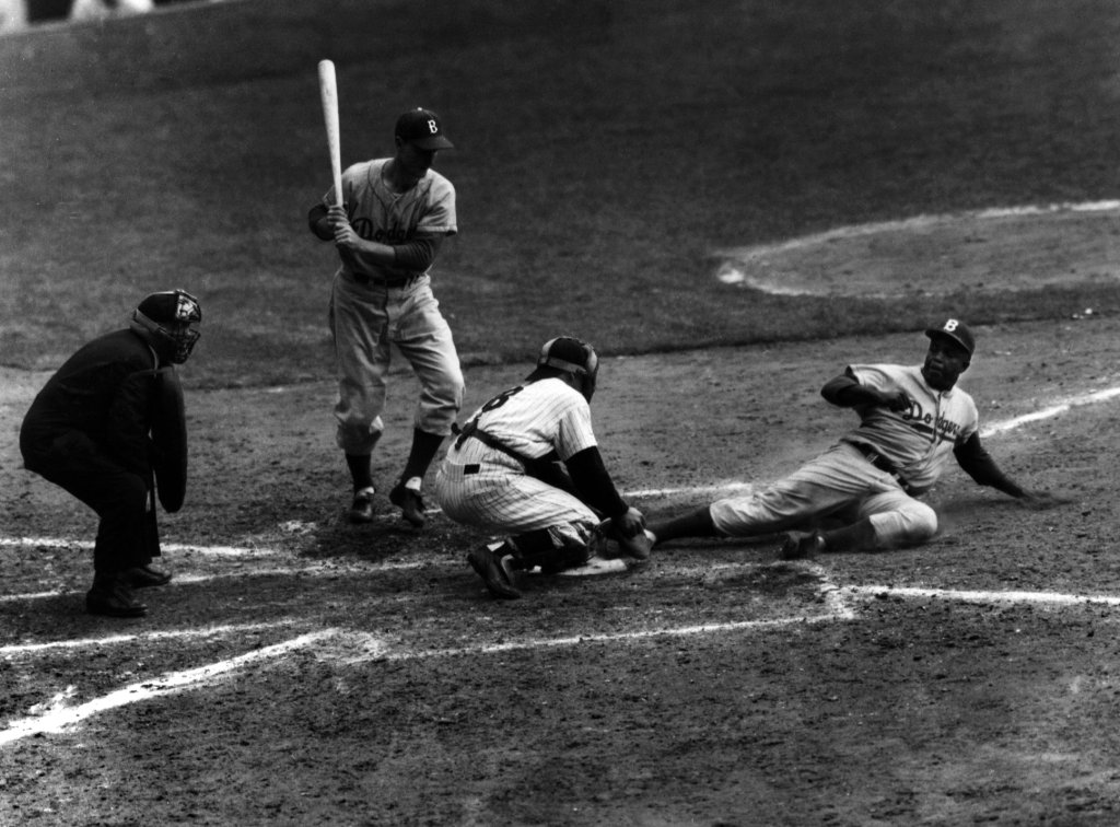 Jackie Robinson safely steals home plate under the tag attempt of Yankees catcher Yogi Berra in the eighth inning of the World Series opener Sept. 28, 1955 in New York's Yankee Stadium.