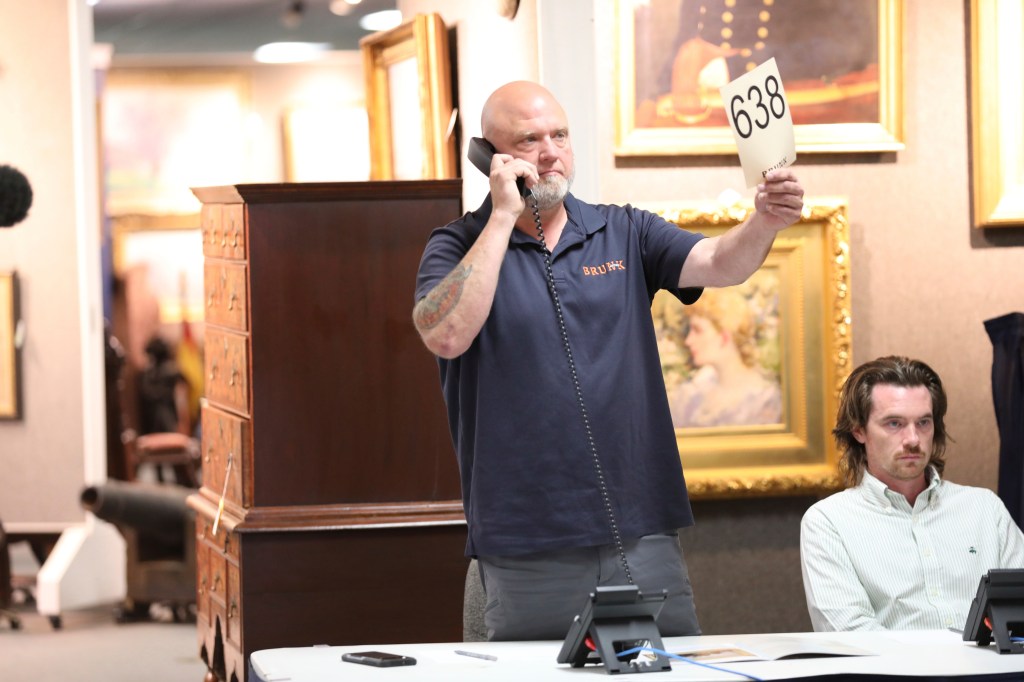 A Brunk auction employee holds up a bidding card as he waits to hear if a bidder on the phone wants to make a bid during the auction on Thursday.