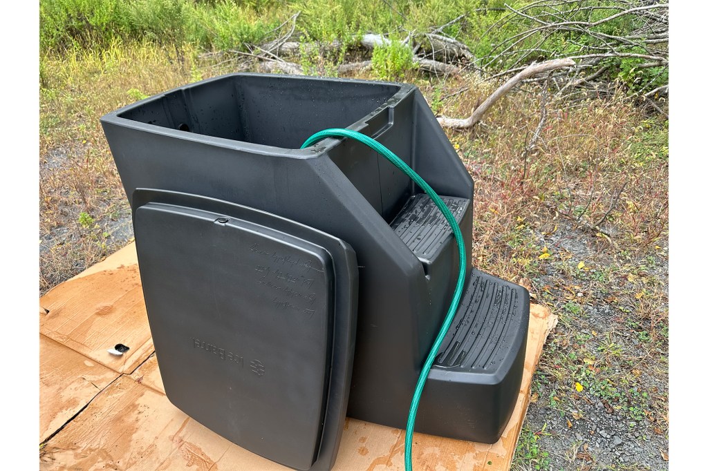 Black plastic container with a green hose on top known as an Ice Barrel 500