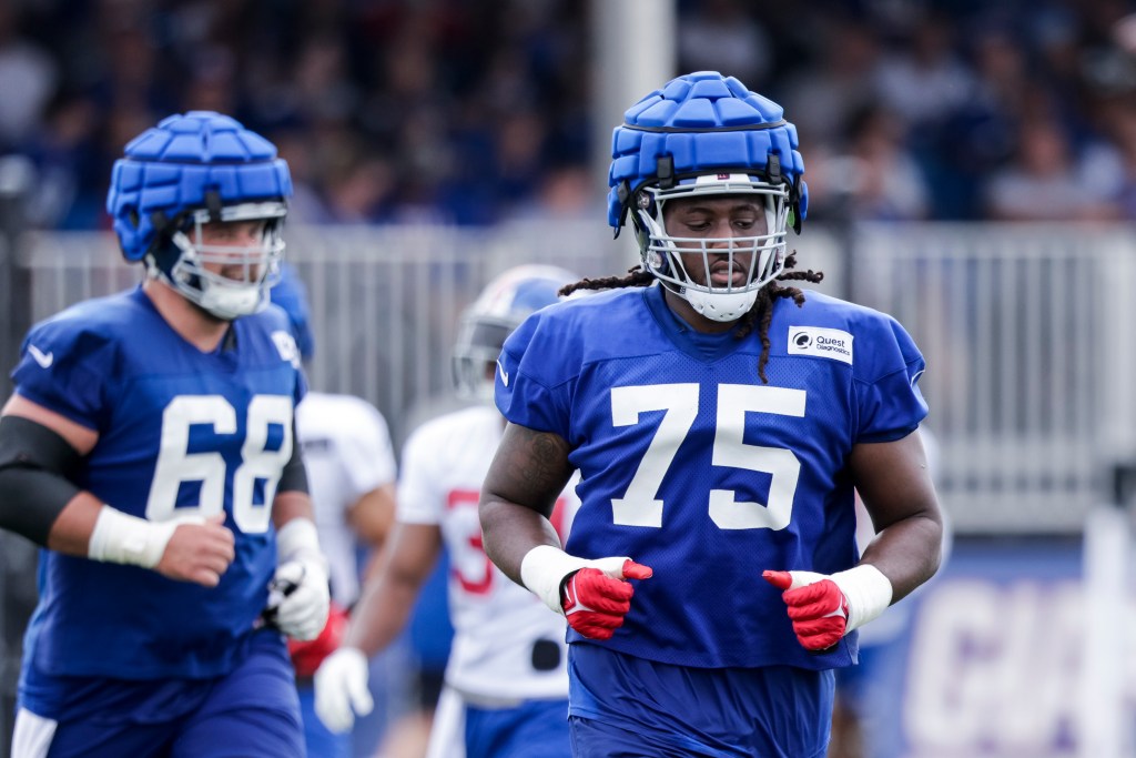 New York Giants player Joshua Ezeudu (75) running during training camp in East Rutherford, NJ, with Devin Fuller and Isaiah Frey in background.