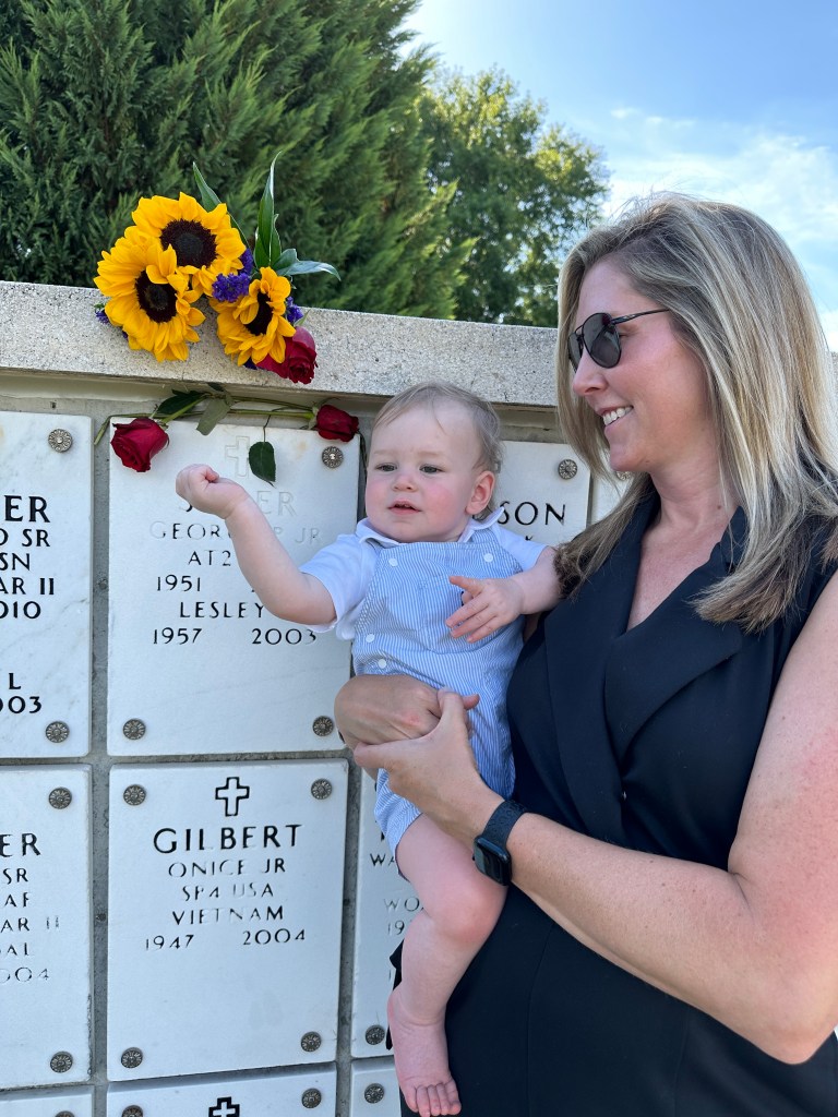 Lauren Sisler holding her baby son in front of a burial wall