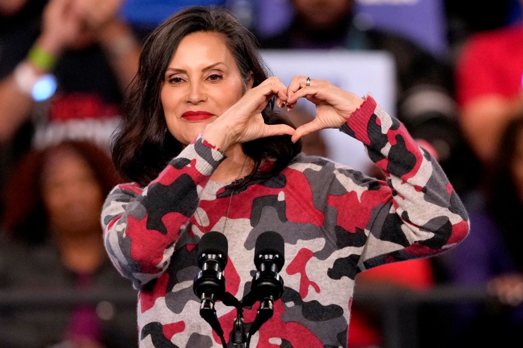 Michigan Governor Gretchen Whitmer making a heart gesture with her hands while speaking before Vice President Kamala Harris at a campaign rally in Flint, Michigan, 2024.