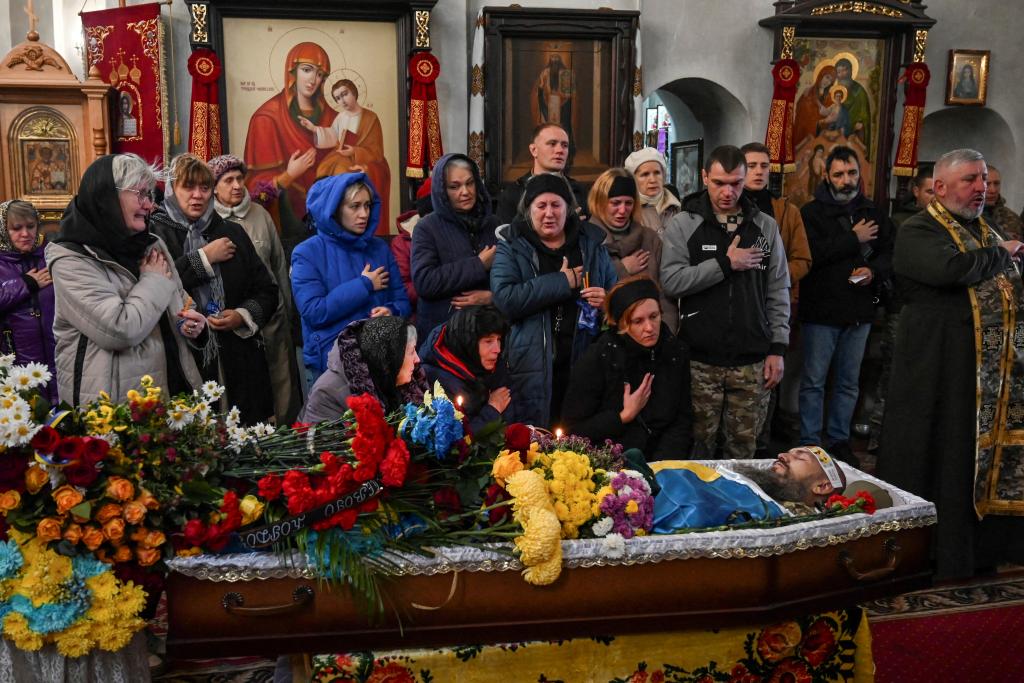 People sing the national anthem during a funeral service for Ukrainian serviceman killed in the war with Russia.