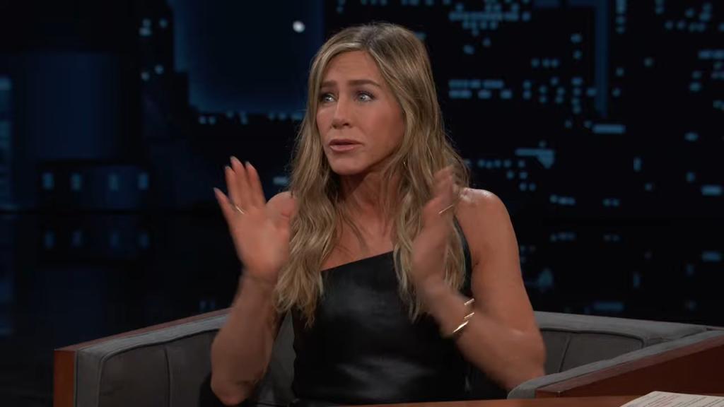 Jennifer Aniston sitting in a chair with her hands up during an appearance on Jimmy Kimmel Live!