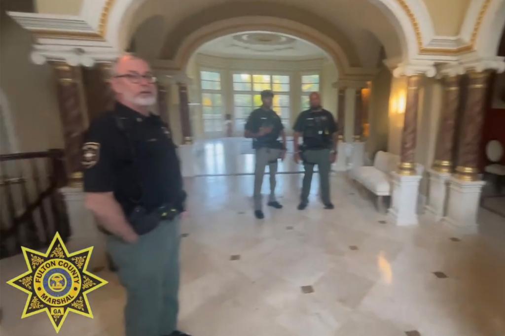 Officers stand in the foyer of the mansion.