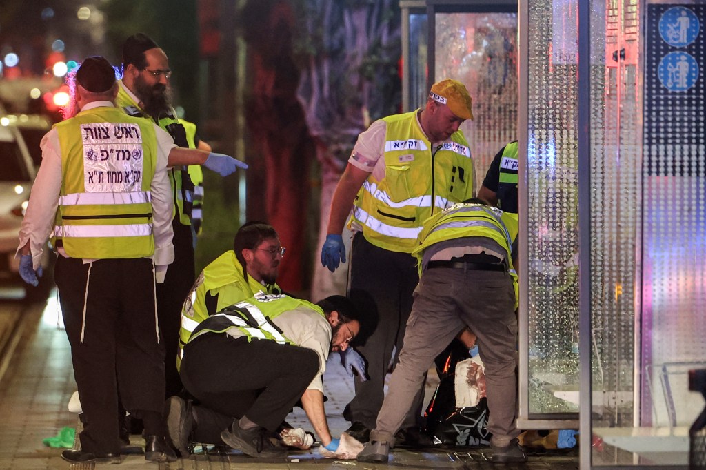 Volunteers from the Zaka Israeli ultra-Orthodox Jewish emergency response team in reflective vests sweeping at the scene of a shooting attack at the Ehrlich station of the Tel Aviv Light Rail