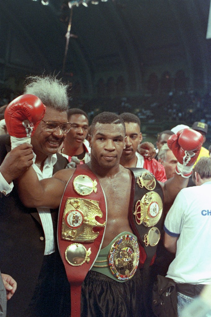 Mike Tyson celebrates his victory over Carl Williams as boxing promoter Don King Walks by his side.