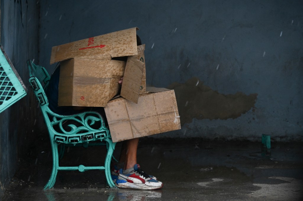 A person uses cardboard boxes to be protected from the wind and rain in Havana.