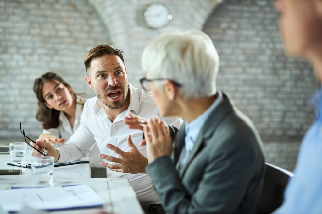 Angry entrepreneur yelling at a colleague during office meeting