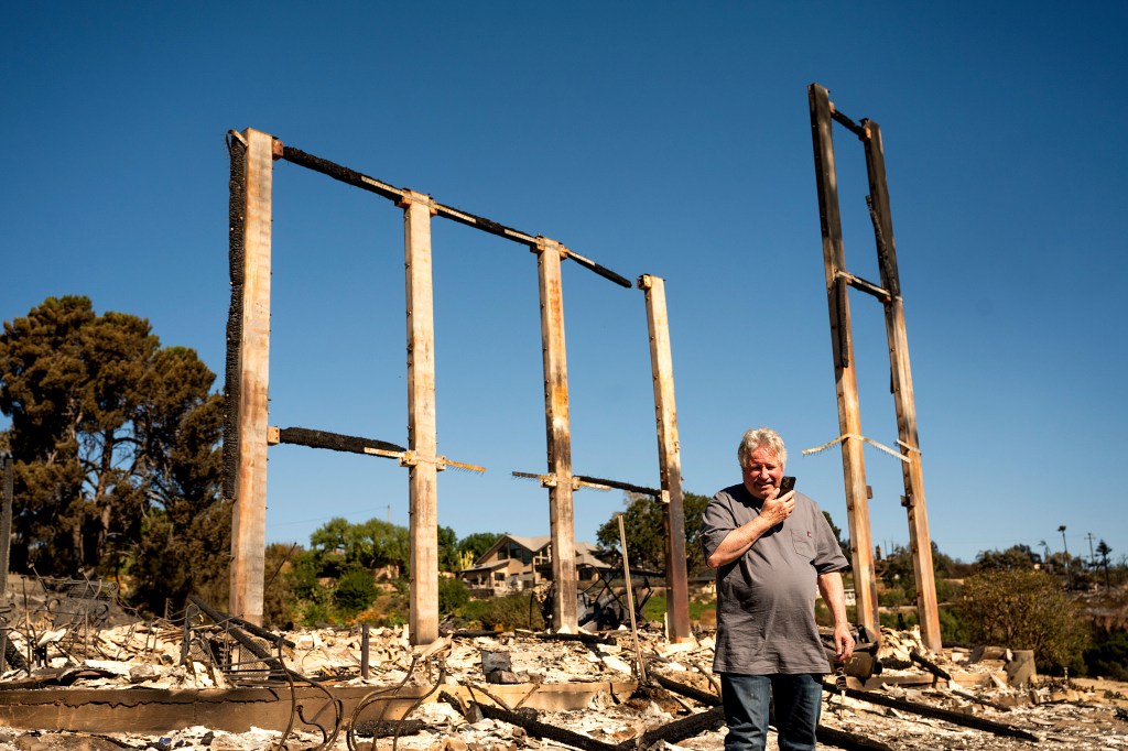 Joey Parish phones his wife, Friday, Nov. 8, 2024, while standing in front of his home, which was destroyed by the Mountain Fire in Camarillo, Calif. 