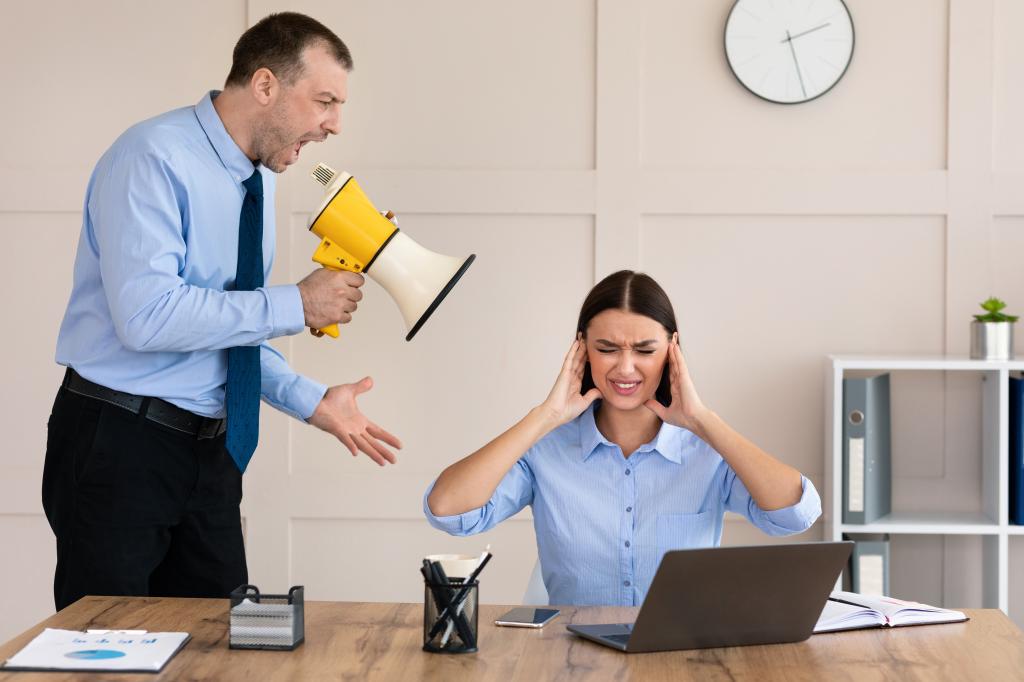 Aggressive Boss. Angry Businessman Shouting Bullying Female Employee Holding Megaphone In Modern Office.