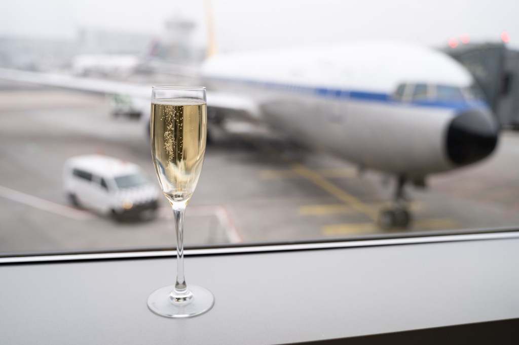 Champagne glass on the window sill of an airplane at an airport.