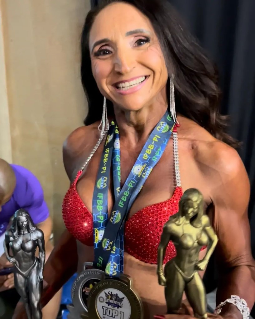 Claudia Oliveira in a sparkly red bikini with medals and trophies at a weightlifting competition.