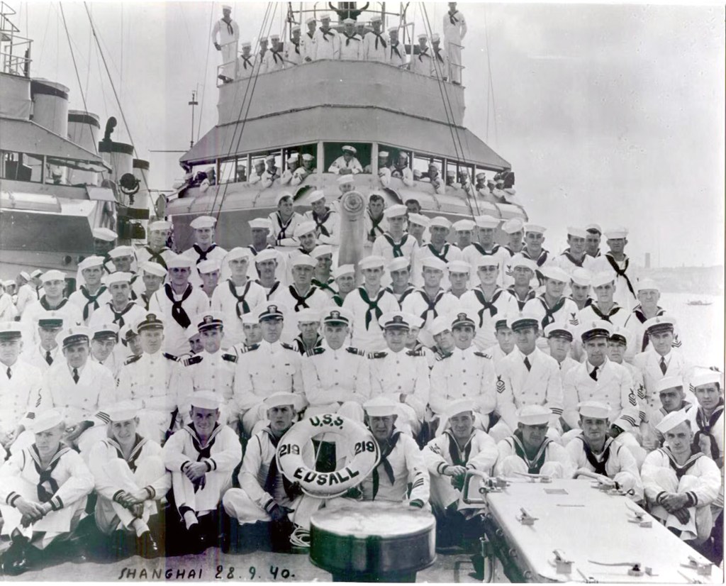 Historic black and white picture of a few dozen sailors on the deck of the USS Edsall