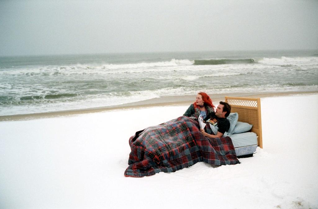 Jim Carrey and Kate Winslet lying in a bed on a beach in a scene from the movie 'Eternal Sunshine of the Spotless Mind' (2004)