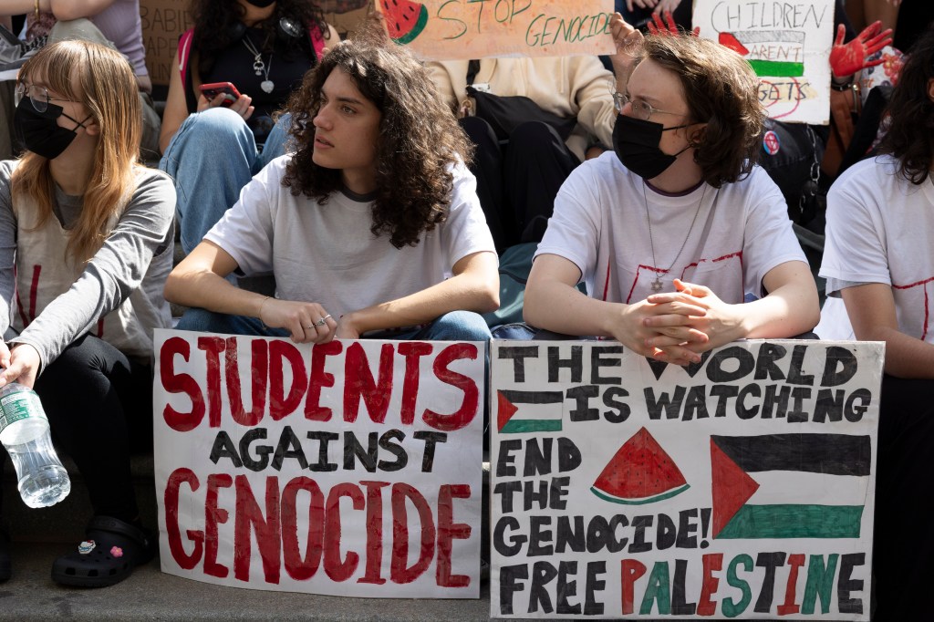 Students hold signs that read 'STUDENTS AGAINST GENOCIDE' 'THE WORLD IS WATCHING END THE GENOCIDE! FREE PALESTINE.'