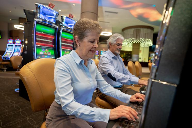 Senior couple focused and enjoying their time while gambling on slot machines at the casino