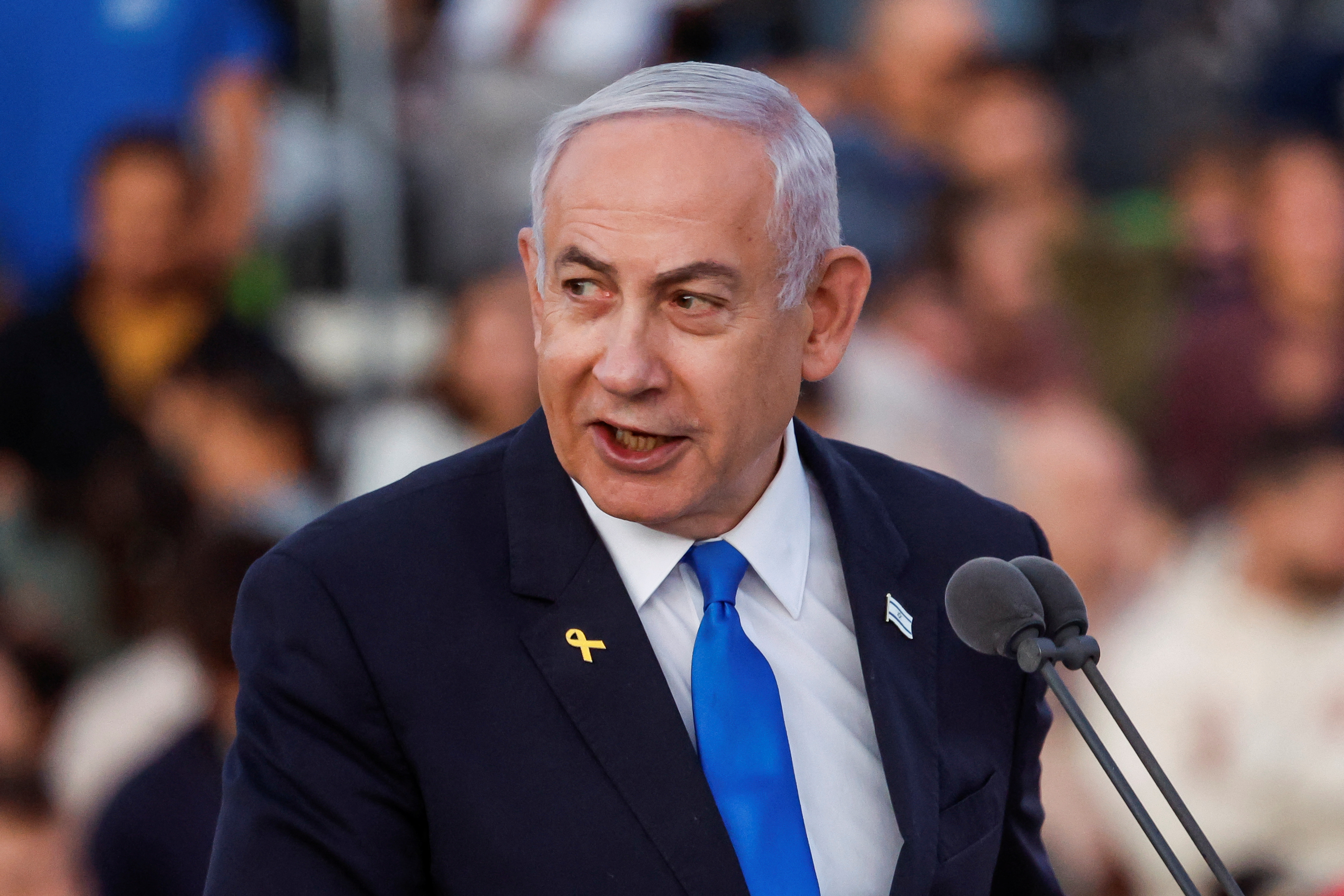 Israeli Prime Minister Benjamin Netanyahu in a suit and tie speaking into a microphone