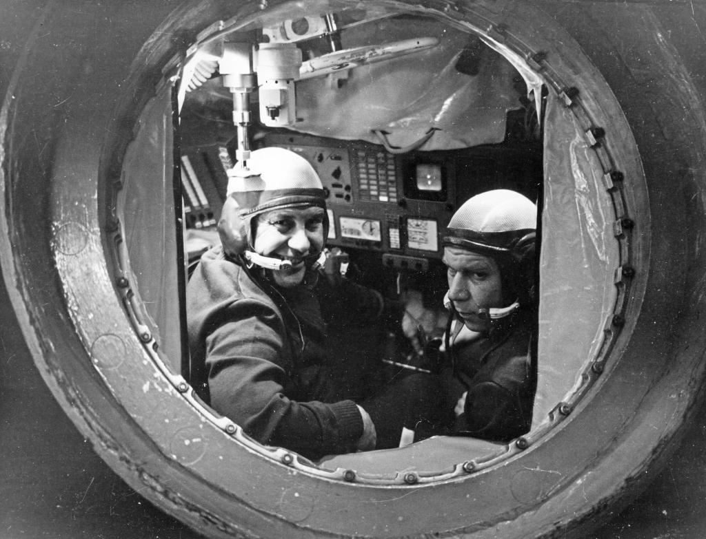 The crew of the Soviet space mission Soyuz 14 look through a window in space.