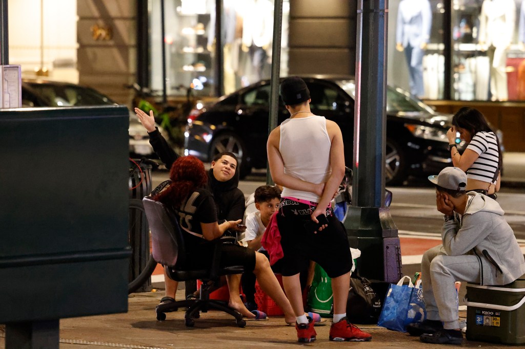 Migrants sitting outside the shelter at the Roosevelt Hotel 