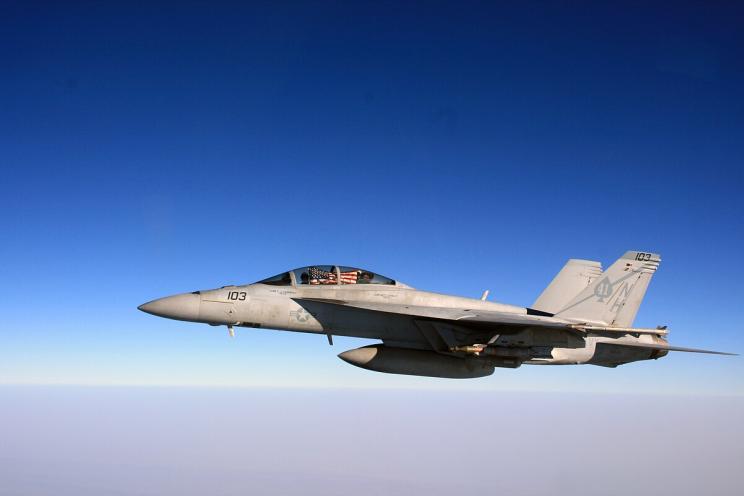 A fighter jet with American flag in the sky.