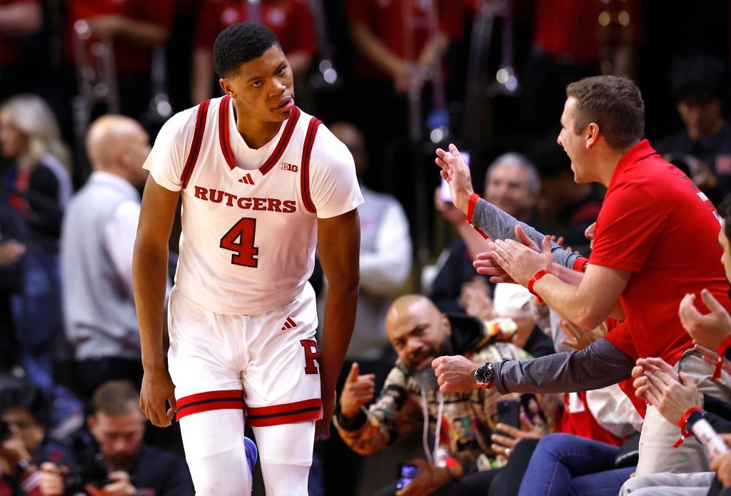 Rutgers guard Ace Bailey (4) celebrating after making a three-point shot in a college basketball game against Monmouth, while the crowd watches.