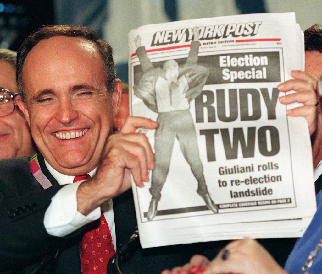 Giuliani holding a picture of a New York Post cover of him winning re-election.