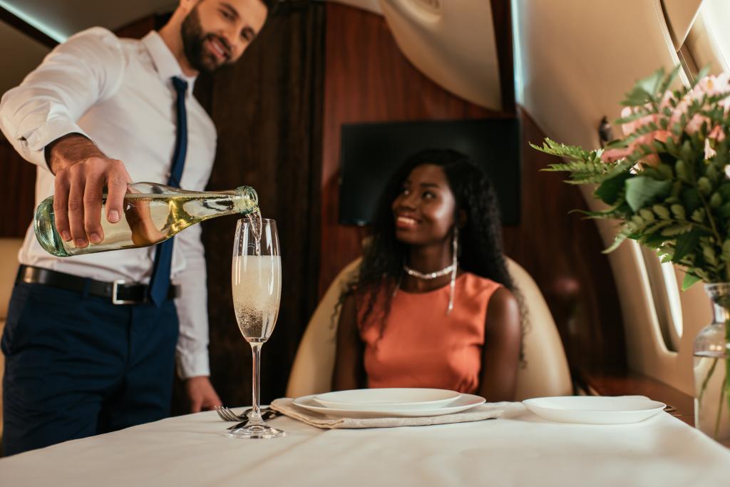 (Left) A flight attendant serving a first-class passenger champagne.