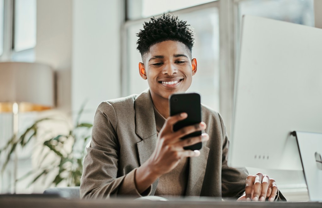 A young man on his phone at work. 