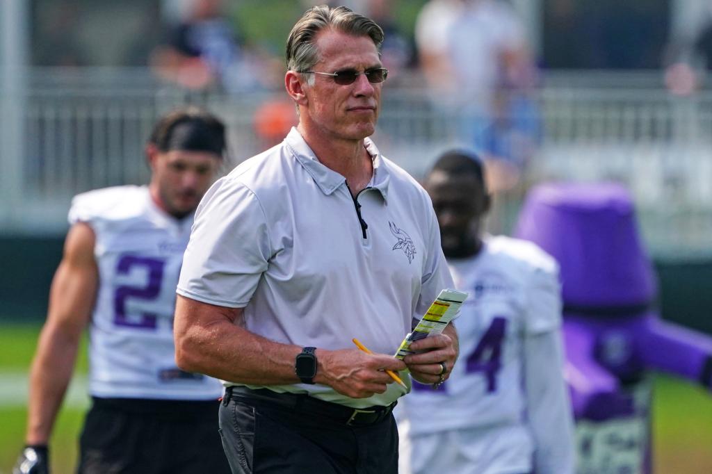 Rick Spielman, former Minnesota Vikings general manager, holding a book and a pen at the Vikings Training Camp.