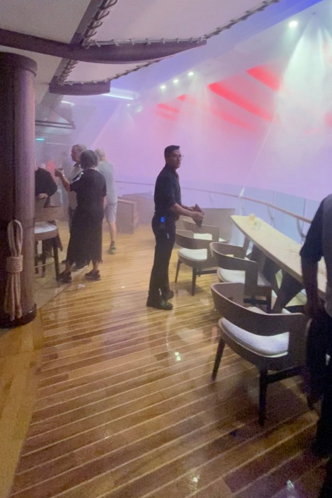 Passengers on Royal Caribbean's Symphony of the Seas look on in bewilderment as sprinkler system unexpectedly soaks the cruise ship during Halloween party