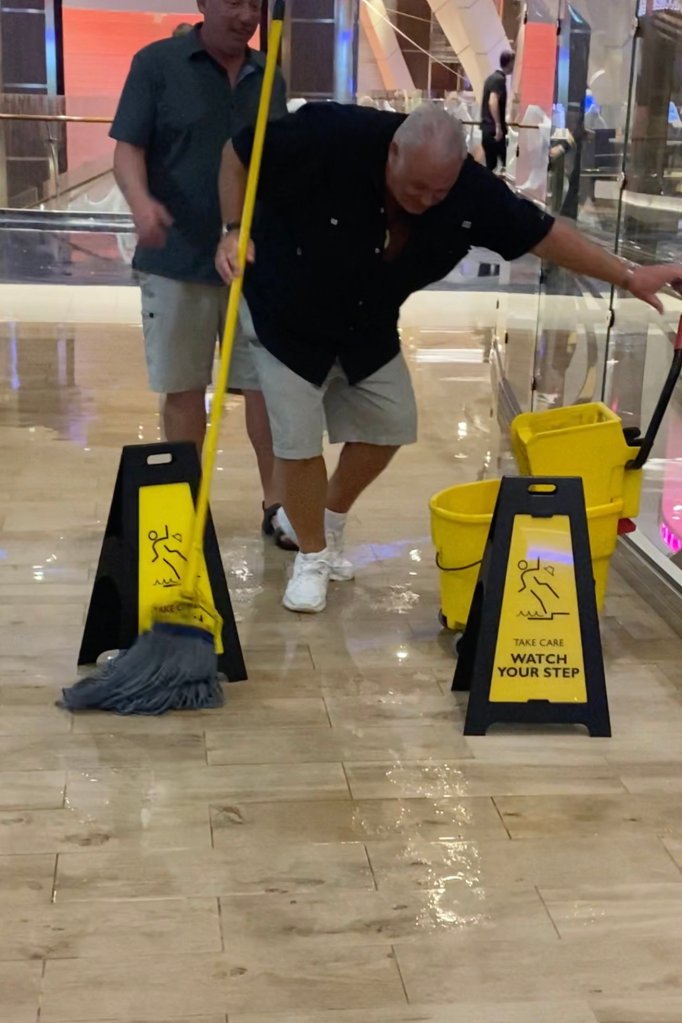 A man mopping water from walkways on the Royal Caribbean cruise ship after a sprinkler mishap