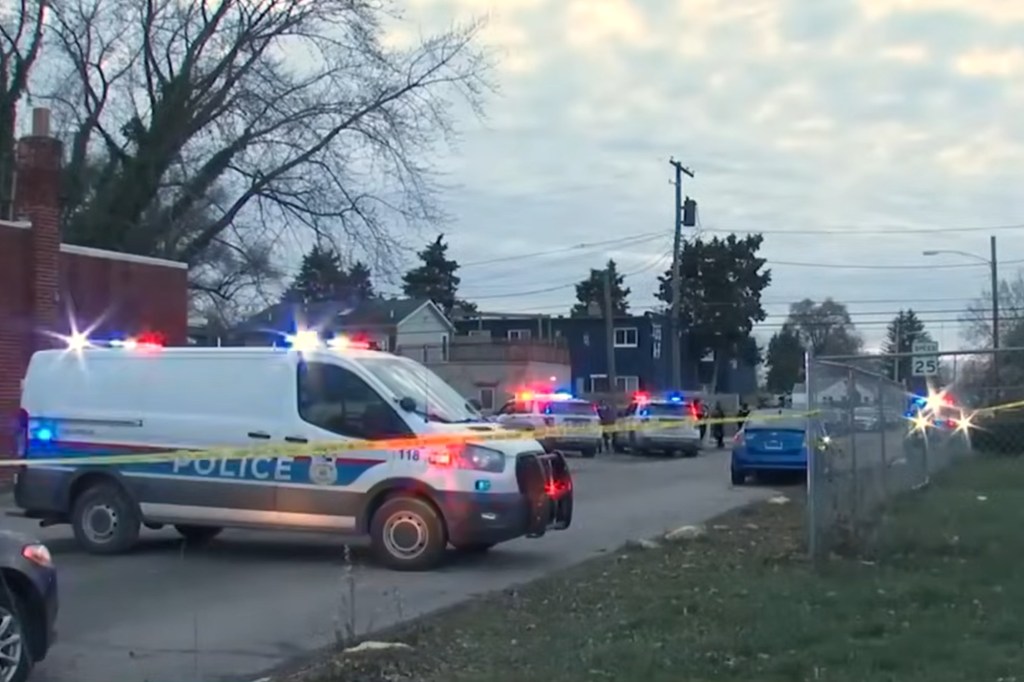 Police vehicles inside a suburban crime scene cordoned off by yellow tape.