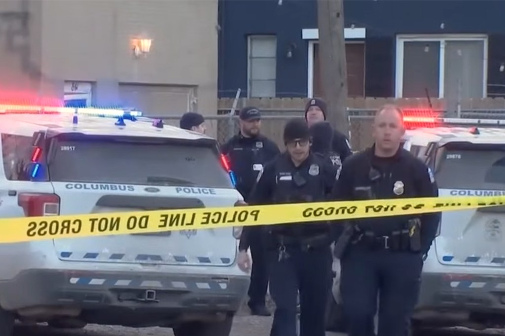 Police officers outside a house with crime scene tape in the foreground.