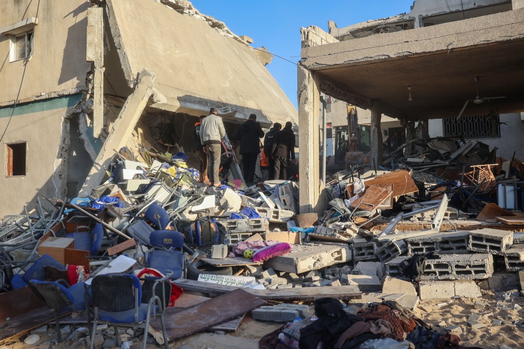 Rescuers and civilians searching through building rubble for survivors after an Israeli strike in the central Gaza Strip, December 14, 2024