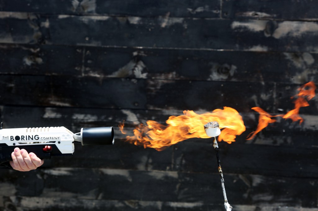 An attendee operates a Boring Co. flamethrower to toast a marshmallow during the company's Not-a-Flamethrower Party outside of the Space Exploration Technologies Corp.