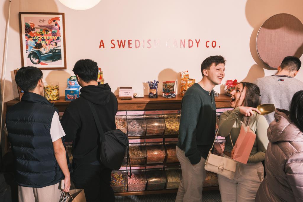 A group of people standing in front of BonBon, a popular Swedish candy store in Manhattan, New York