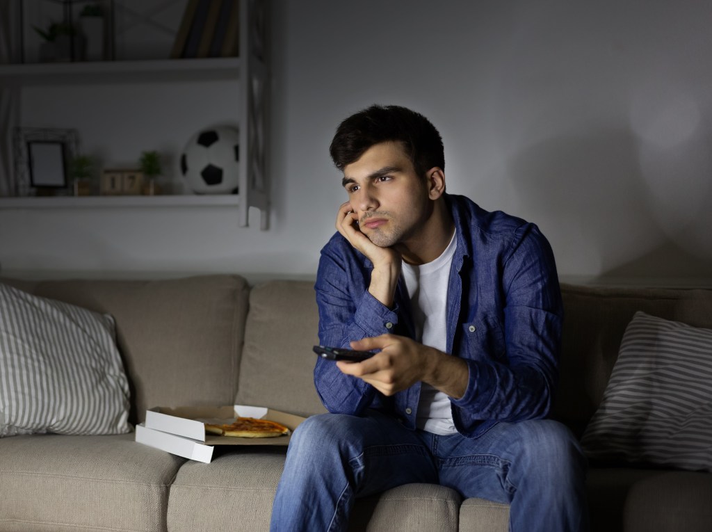 Man on couch alone watching TV.