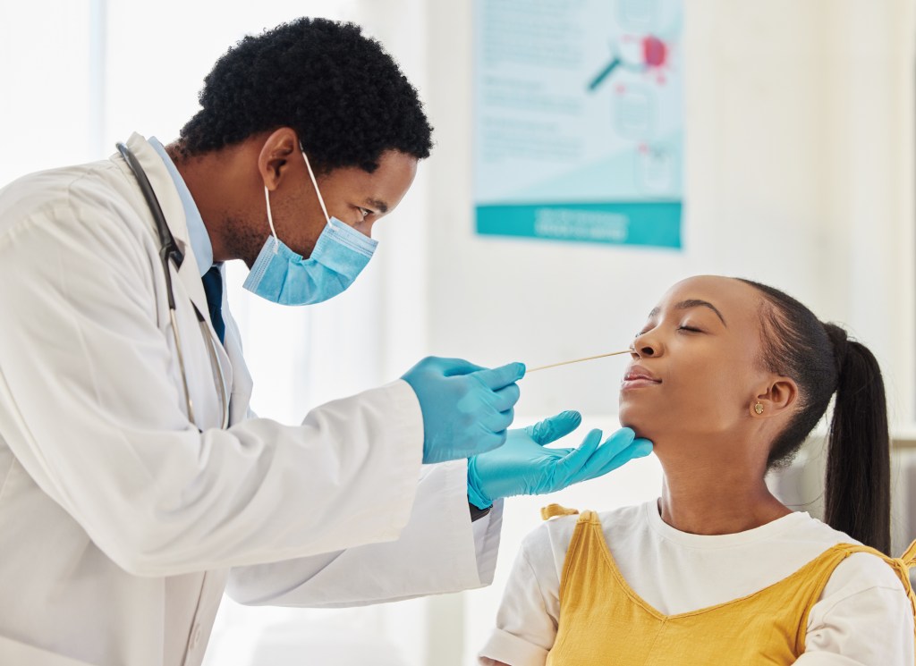 COVID-19 symptoms include fever or chills, cough, breathing troubles, sore throat, congestion or a runny nose, loss of taste or smell, fatigue, muscle or body aches, headache, nausea or vomiting and diarrhea. Here, a woman gets her nose swabbed in a medical setting.